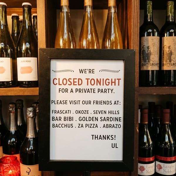 A "Closed Tonight" sign stands amidst shelves filled with various wine and champagne bottles.