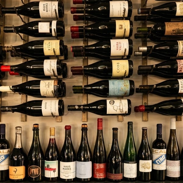 A wall display of numerous wine bottles, some racked horizontally, others standing upright.