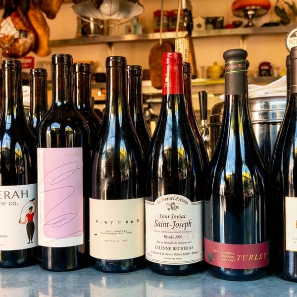 A diverse selection of red wine bottles with various labels displayed on a counter.