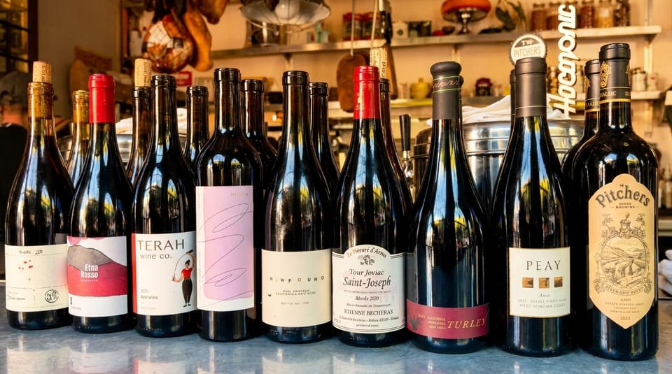 A diverse selection of red wine bottles with various labels displayed on a counter.