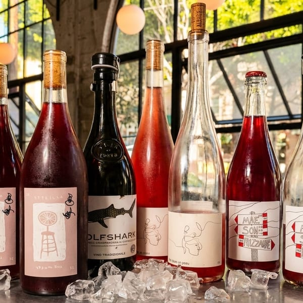 Assortment of wine bottles with unique labels and ice cubes on a table in a restaurant.